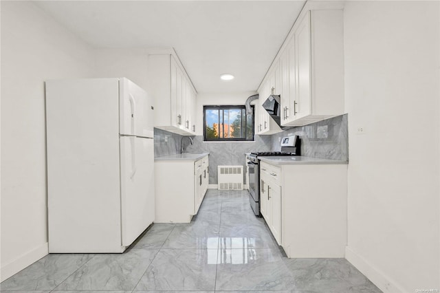 kitchen featuring sink, exhaust hood, stainless steel gas stove, white fridge, and white cabinetry