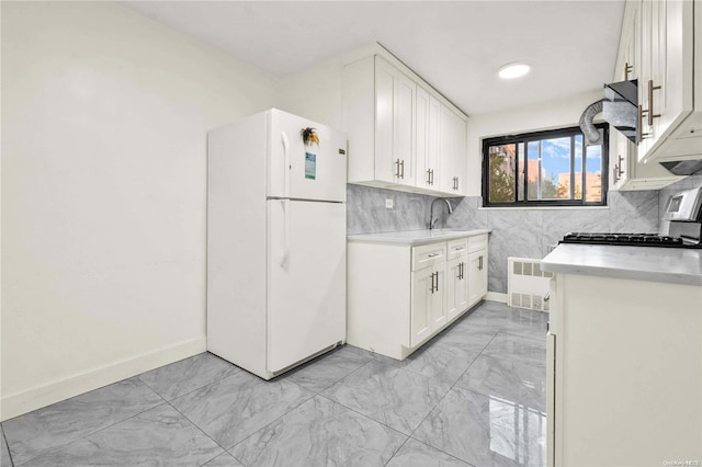 kitchen with white cabinets, sink, tasteful backsplash, white fridge, and radiator heating unit