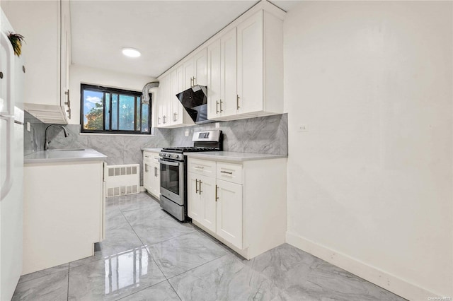 kitchen with backsplash, white cabinetry, stainless steel range with gas cooktop, and sink