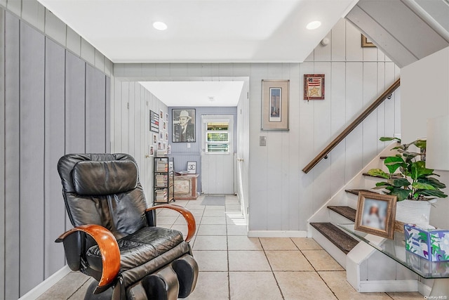 sitting room with light tile patterned flooring and wood walls