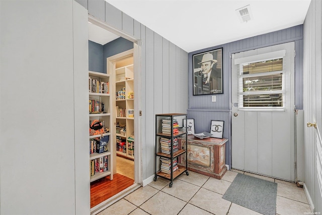 doorway to outside with wood walls and light tile patterned flooring