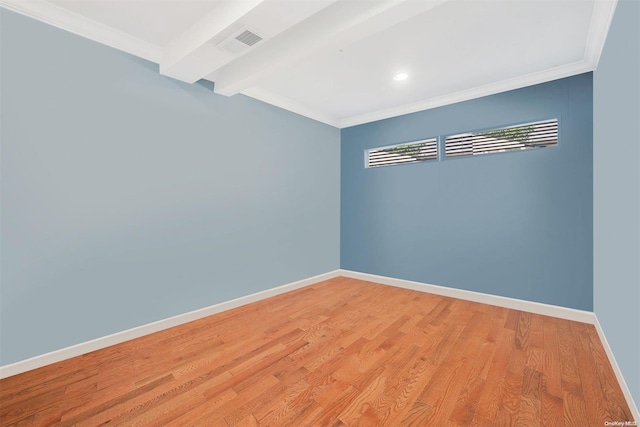 empty room featuring beamed ceiling, light hardwood / wood-style floors, and ornamental molding