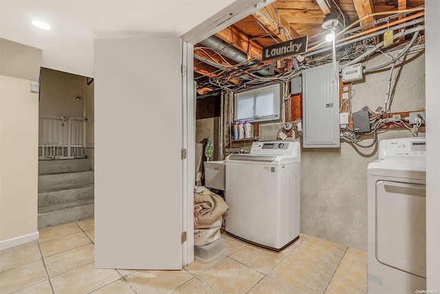 laundry area with light tile patterned floors, electric panel, and washing machine and clothes dryer