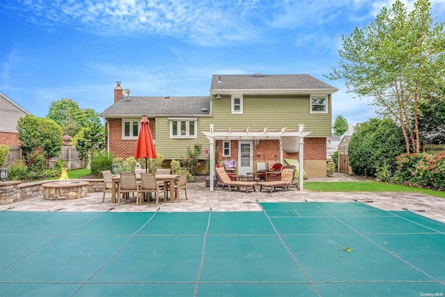 rear view of house featuring a pergola, a covered pool, a patio, and a fire pit