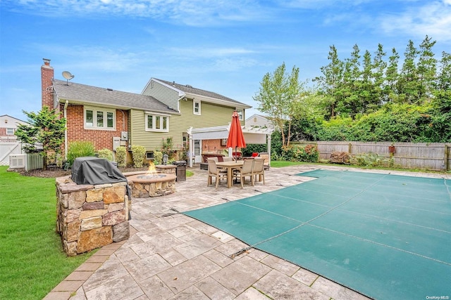 view of swimming pool featuring a grill, a yard, a patio, and a fire pit