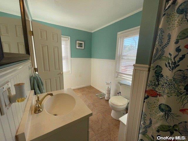 bathroom featuring tile patterned flooring, vanity, toilet, and ornamental molding