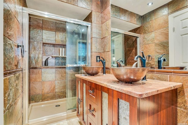 bathroom featuring a shower with door, vanity, and tile walls