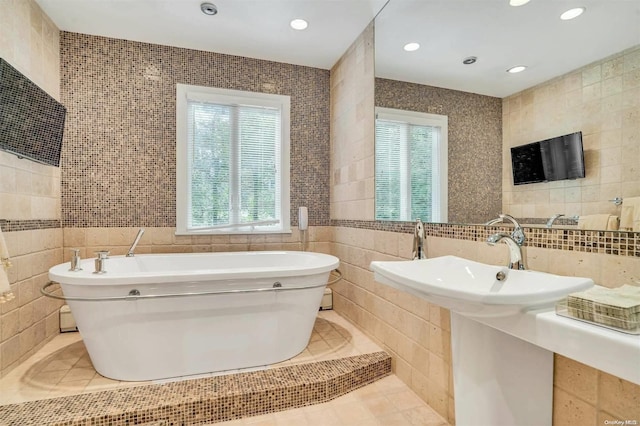 bathroom featuring tile patterned flooring, a bathtub, and tile walls