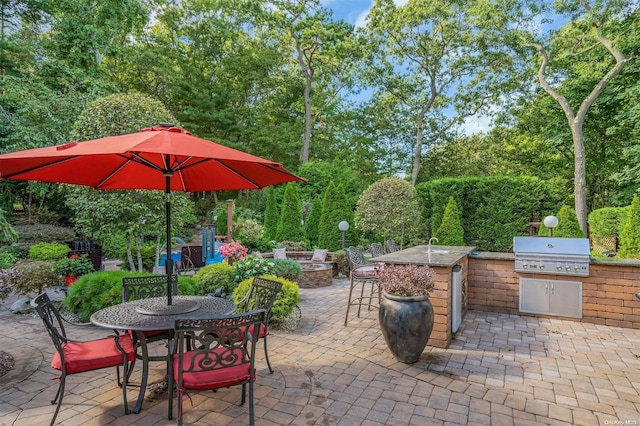 view of patio / terrace featuring grilling area, a fire pit, and an outdoor kitchen