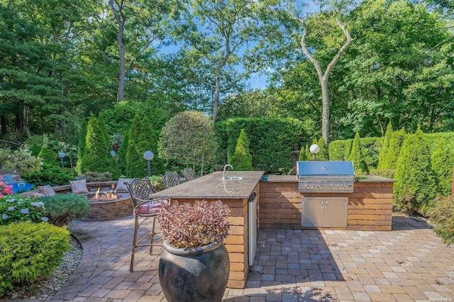 view of patio / terrace with area for grilling, a wet bar, and an outdoor fire pit