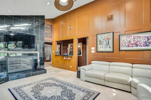 living room with a fireplace, a towering ceiling, and ceiling fan