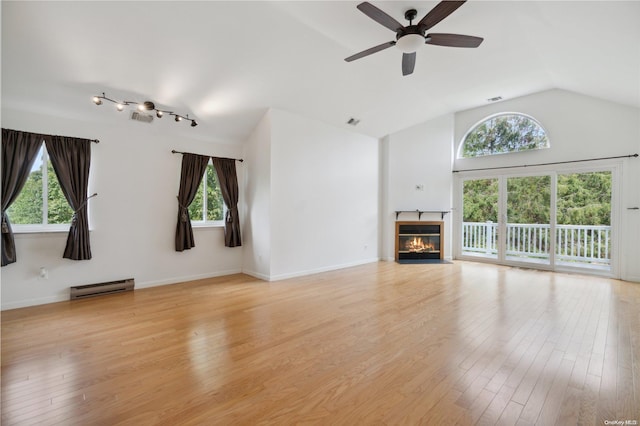 unfurnished living room with light wood-type flooring, a wealth of natural light, and vaulted ceiling