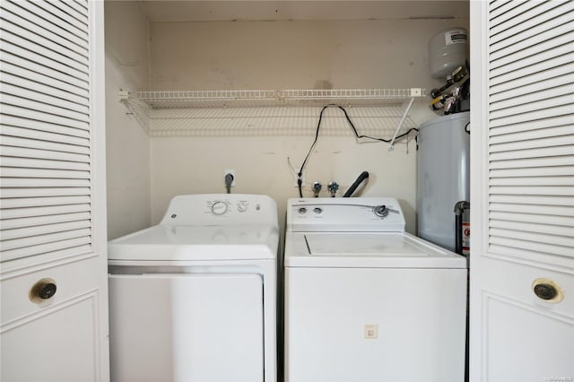 clothes washing area with washing machine and dryer and water heater