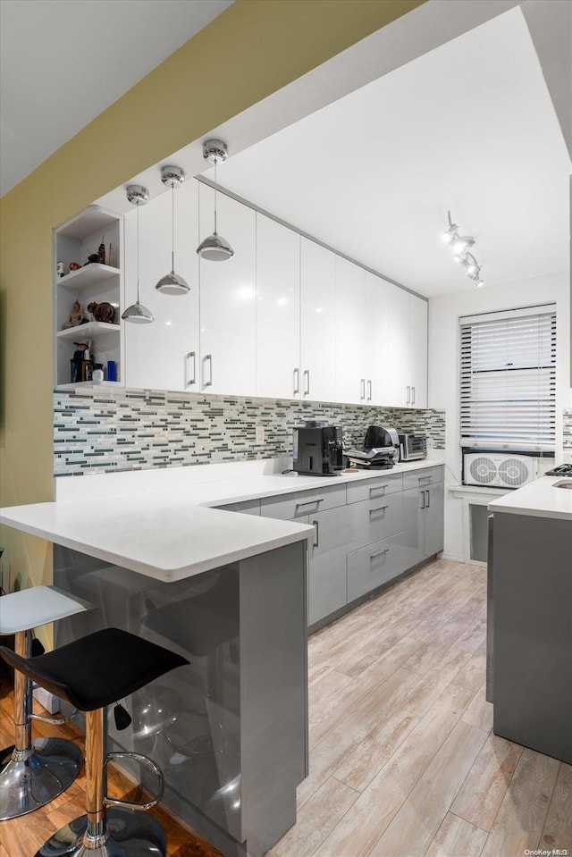 kitchen with a kitchen bar, kitchen peninsula, pendant lighting, and light hardwood / wood-style floors