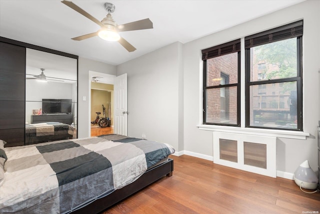 bedroom with ceiling fan, wood-type flooring, and a closet