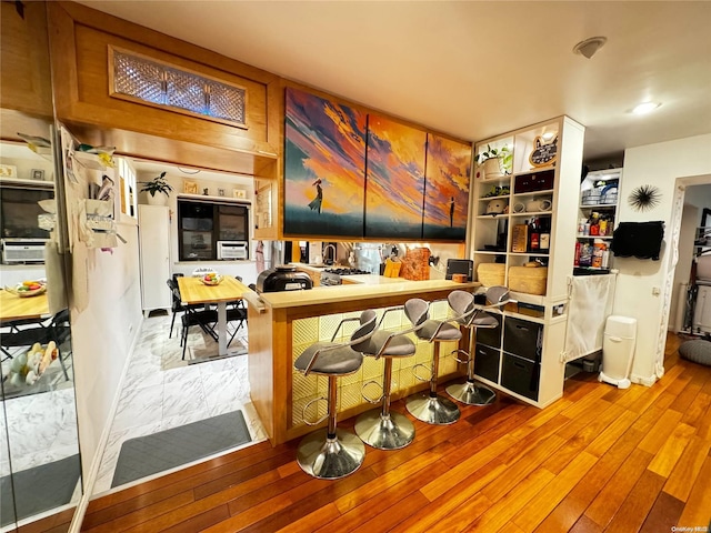 kitchen with a kitchen breakfast bar, light wood-type flooring, and kitchen peninsula