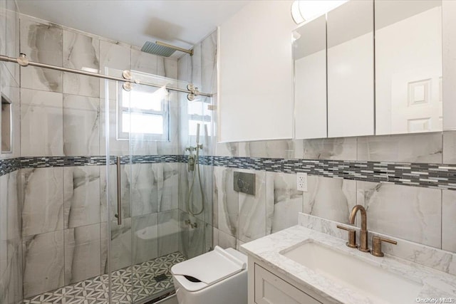 bathroom with vanity, toilet, a shower with door, and tile walls