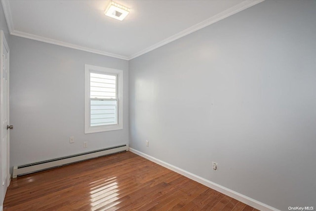 spare room featuring hardwood / wood-style flooring, crown molding, and a baseboard heating unit