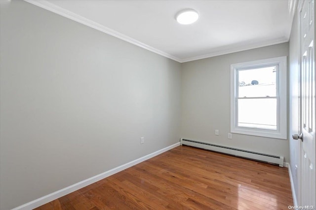 spare room with wood-type flooring, a baseboard radiator, and crown molding