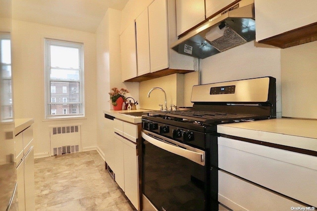 kitchen with radiator heating unit, gas stove, white cabinetry, and sink