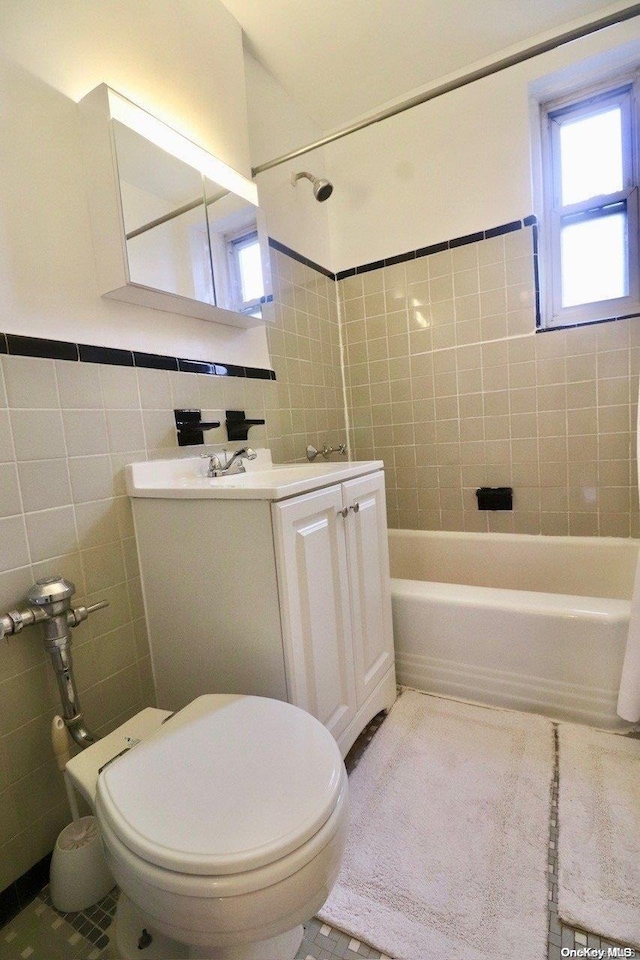 full bathroom featuring tile patterned flooring, toilet, vanity, tile walls, and tiled shower / bath