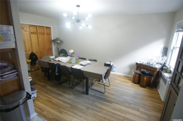 dining room with wood-type flooring, radiator heating unit, and an inviting chandelier