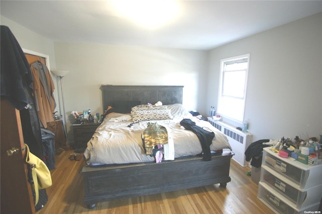 bedroom featuring hardwood / wood-style floors and radiator heating unit