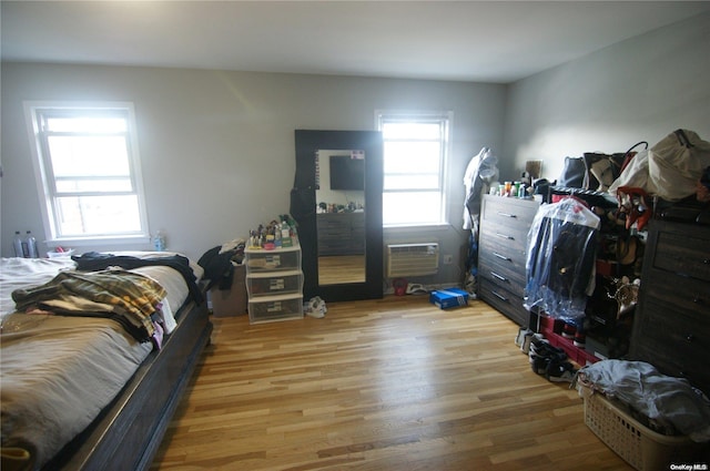 bedroom featuring a wall unit AC and light hardwood / wood-style flooring