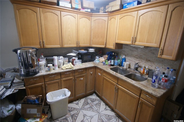 kitchen featuring decorative backsplash, light stone countertops, and sink