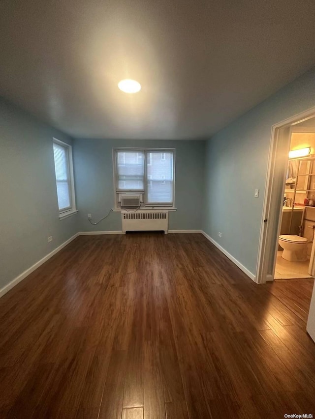 empty room featuring radiator heating unit and dark hardwood / wood-style floors