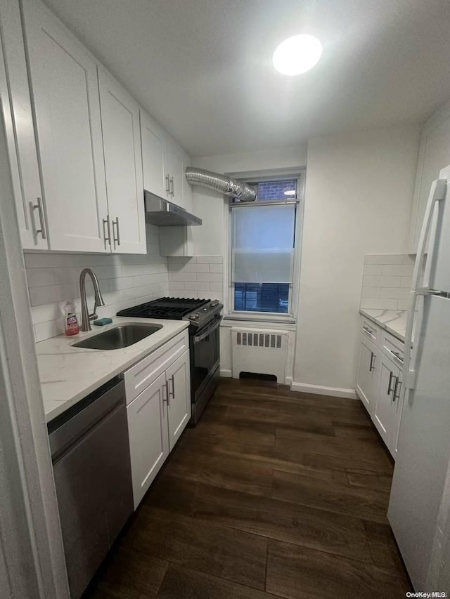 kitchen featuring radiator, sink, appliances with stainless steel finishes, light stone counters, and white cabinetry