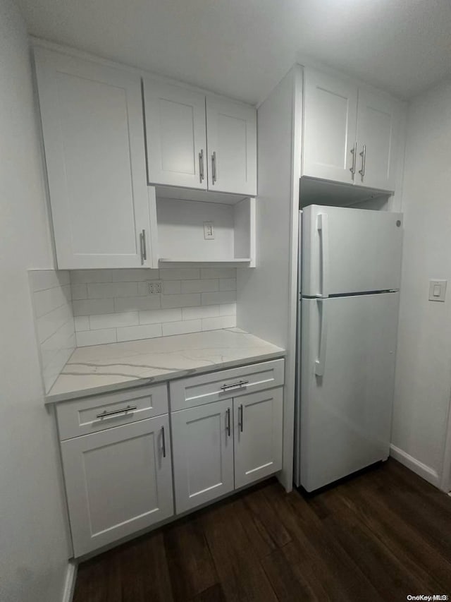 kitchen with white cabinets, decorative backsplash, white fridge, and dark hardwood / wood-style floors