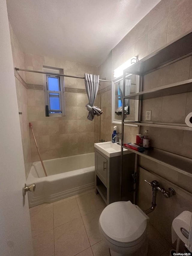 full bathroom with vanity, tile patterned floors, tiled shower / bath, toilet, and tile walls