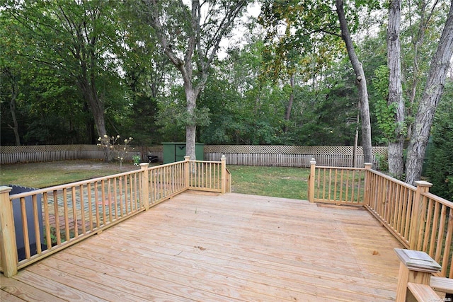 wooden terrace with a storage shed and a lawn