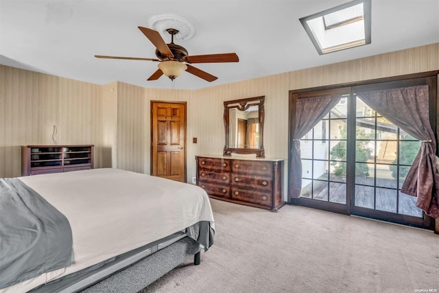 bedroom with access to exterior, ceiling fan, light colored carpet, and a skylight