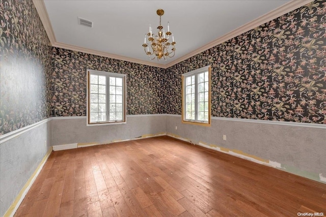 empty room featuring hardwood / wood-style flooring, an inviting chandelier, and plenty of natural light