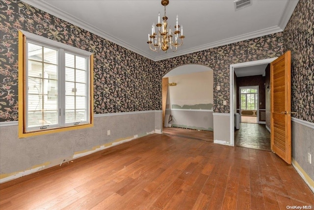 unfurnished room with wood-type flooring, ornamental molding, and a chandelier