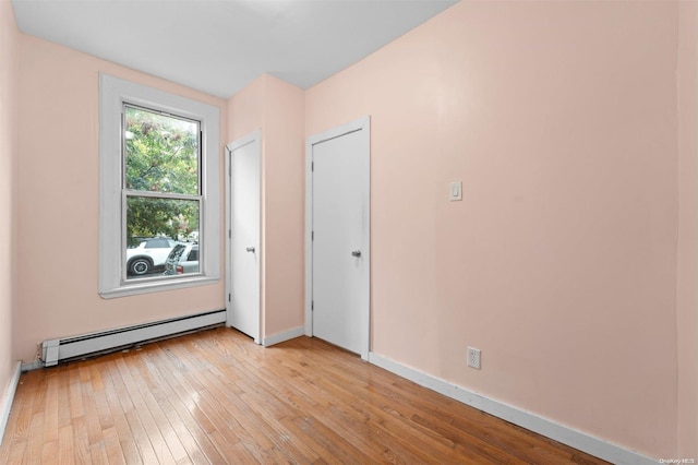 unfurnished room featuring light wood-type flooring and a baseboard heating unit