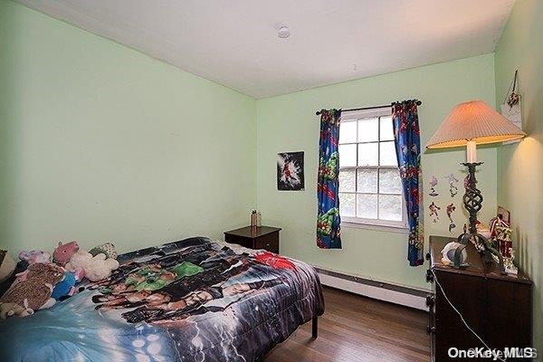 bedroom featuring dark hardwood / wood-style flooring and a baseboard heating unit