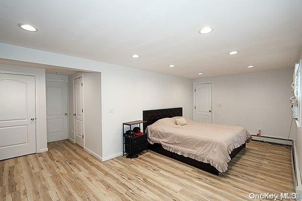 bedroom featuring light wood-type flooring and baseboard heating