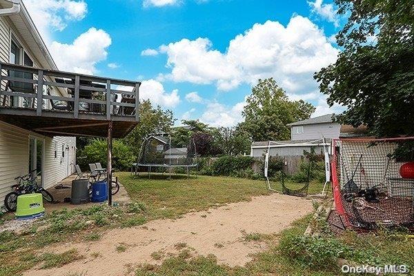 view of yard with a trampoline and a wooden deck