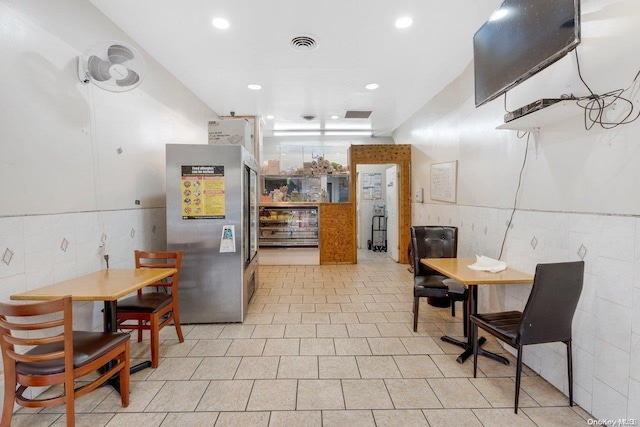 kitchen featuring stainless steel fridge and tile walls