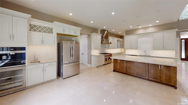 kitchen featuring white cabinetry, stainless steel appliances, and wall chimney range hood