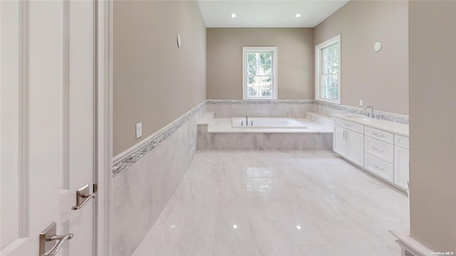 bathroom featuring vanity and tiled bath