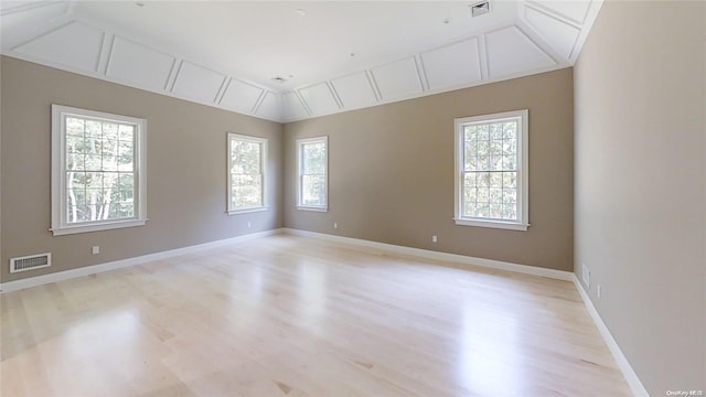 spare room featuring lofted ceiling, plenty of natural light, visible vents, and baseboards