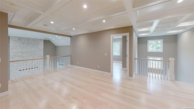 empty room with beam ceiling, baseboards, coffered ceiling, and wood finished floors