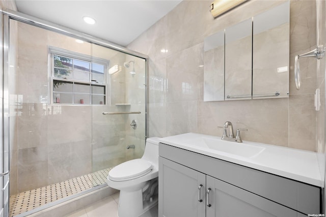 bathroom featuring walk in shower, tile patterned flooring, toilet, vanity, and tile walls