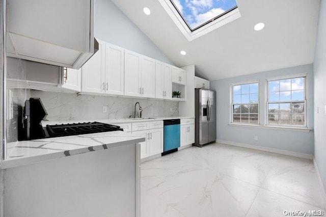 kitchen with appliances with stainless steel finishes, a skylight, light stone counters, sink, and white cabinetry