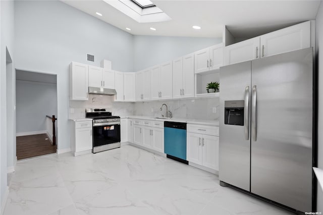 kitchen with high vaulted ceiling, white cabinets, a skylight, tasteful backsplash, and stainless steel appliances