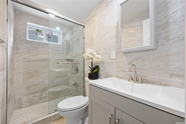 bathroom featuring walk in shower, vanity, toilet, and tile walls